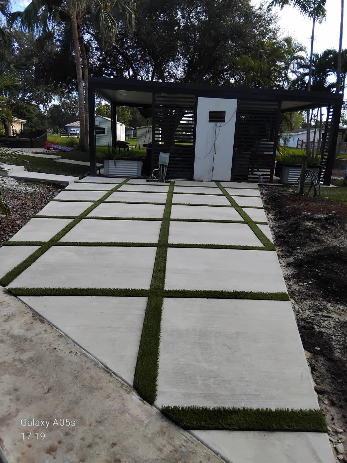 Slab walkway with turf joints leading to a pergola by Concrete Solutions Today, serving Fort Lauderdale, FL