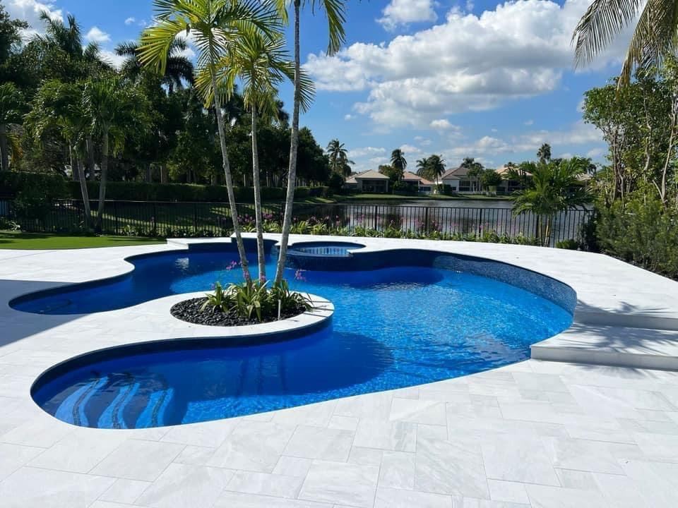 Freeform pool with a palm island and white deck by Concrete Solutions Today, serving Fort Lauderdale, FL